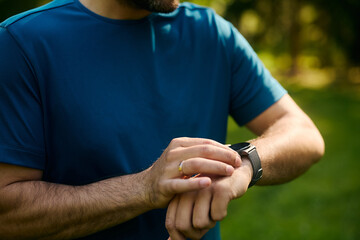Close up of athlete using fitness tracker while working out in park.