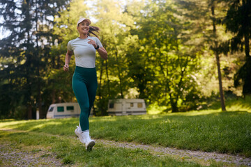 Full length of happy woman jogging in park.