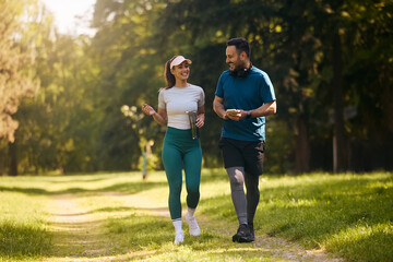 Happy couple of athletes talking while walking in  park.