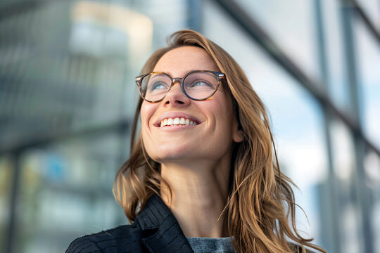 a woman with glasses smiling and looking up