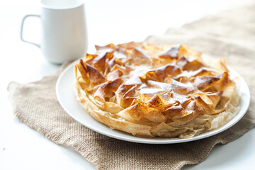 Homemade sweet phylla pastry pie with a napkin on the table and a cup of tea. selected focus