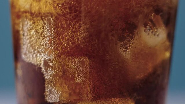 Pouring Cola with ice cubes. Cola with Ice and bubbles in glass.