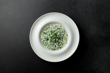Cold soup with fresh cucumbers, sausage, broth and sour cream in a plate-hat on a black background....