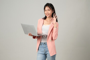 happy asian woman wearing formal casual outfit holding laptop computer giving approval ok sign gesture on isolated background