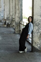 Attractive Caucasian young woman brunette hippie in casual clothes posing on the grounds of an abandoned building while walking on a warm spring day. Style, Fashion, Freedom.