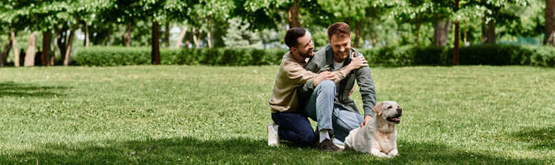 Fototapeta premium Two bearded men, a gay couple, are enjoying a sunny day in the park with their labrador retriever.
