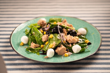 Tuna, egg, arugula and black olive salad served on a plate with cutlery.