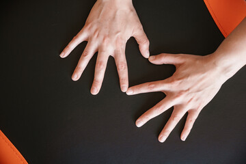 Two hands are touching with heart shape on a black surface