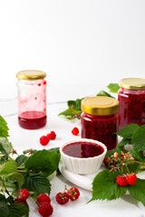 Homemade summer preservation, raspberries jam in jars, jars with jam and raspberry sprigs