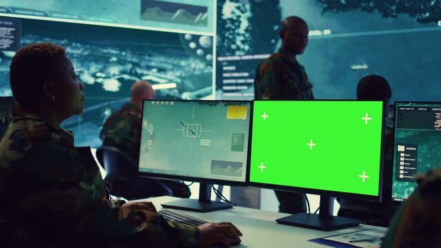 Female navy specialist monitoring warships activity along the national coast line, uses greenscreen to ensure protection. Woman IT operator working in power base command center. Camera B.