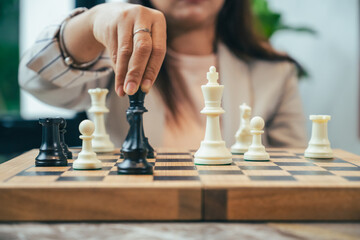 The close-up of a businesswoman’s hand making a checkmate move on a chessboard. The background...