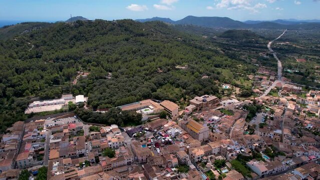 4K Aerial Drone video of beautiful terracotta color town with a massive fort on the hill surrounded by mountains and sea on a sunny summer day, Capdepera, Mallorca