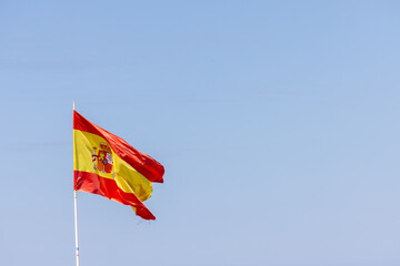Photo of a Spanish flag blowing in the wind on a sunny summers day with a blue sky