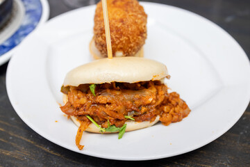 A plate of delicious tapas showing a Chicken tikka masala in a bao bread