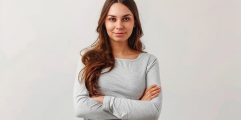 A woman with her arms crossed is looking directly at the camera, giving a confident and introspective expression