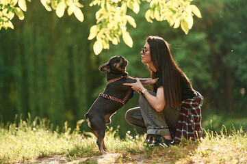 Playing on the grass. Young pretty woman is with her dog in the park