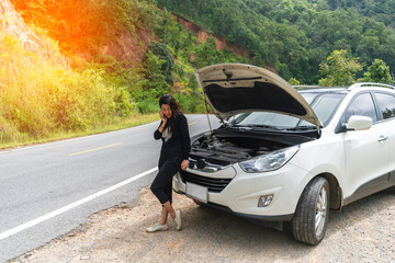 Asian tourist Young woman is calling to car mechanic to repair broken car.