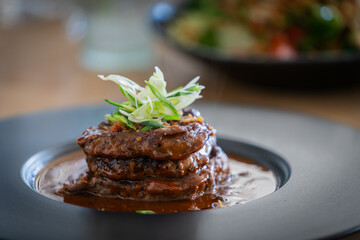 Filet mignon side view. Grilled beef steak on a plate with sauce and garnish. 
