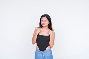 Fototapeta premium A slim and attractive young Asian woman wearing a black bodysuit, teasing about giving a thumbs up, isolated on a white background.