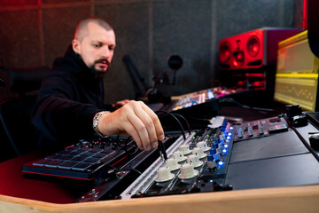 in dark recording studio the sound engineer works with the remote control and connects the wire from the headphones to the remote control