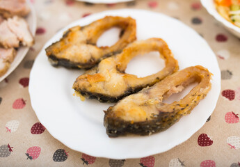 Pieces of the middle part of the carp baked on a white plate