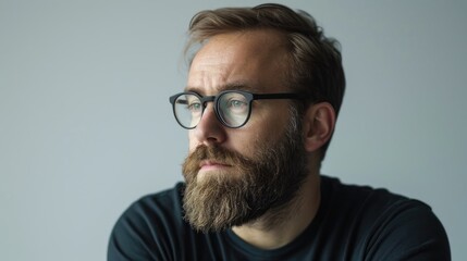 Obraz premium Confident man with beard and glasses thinking portrait against light gray background