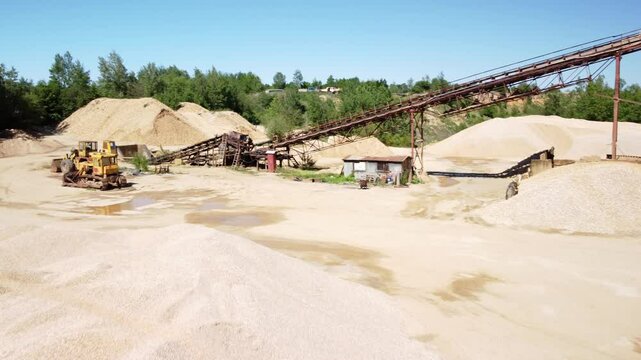 Sand Mounds, a Bulldozer, and a Conveyor Belt in an Old Sand Mine Near the Town of Prudnik, Poland - Drone Flying Forward