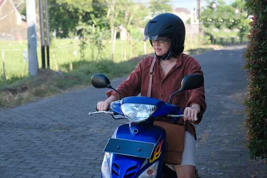 A woman wearing a helmet is about to ride her motorbike