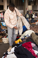 South African guy selects second-hand clothes at a flea market