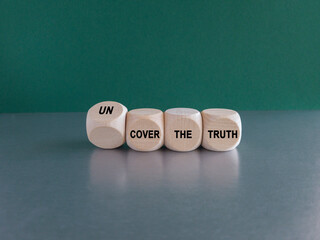 Turned a cube and changes the expression cover the truth to uncover the truth. Beautiful grey table green background.