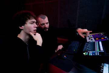 in the recording room dark With neon-lit studio, a sound recorder teaches his junior assistant how...