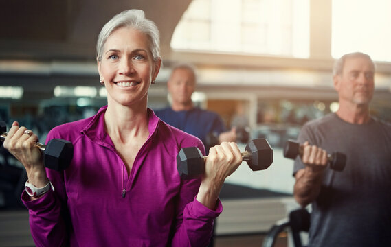 Mature people, woman and dumbbell in class for fitness, coaching and muscle development in gym. Senior group, men and exercise for arms, health and happy for weightlifting workout at wellness club