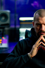 in dark recording studio against the backdrop of musical equipment for sound processing, a young...