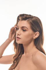 Naklejka premium A young beautiful woman with long wavy hair striking a pose, exuding confidence and elegance.