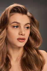 Fototapeta premium A young woman with long wavy brown hair and captivating eyes looks enchanting, banner