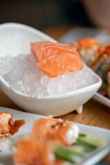 Sashimi slices in a little white bowl with ice on a wooden table. Japanese traditional food.