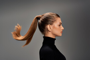 A young woman with long hair styled in a ponytail exudes elegance and grace in this portrait.