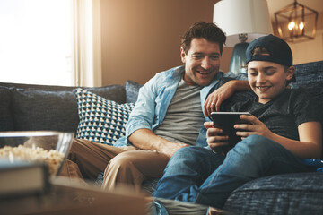 Obraz premium Father, son and relax on sofa with tablet for online streaming service, movies or video games on holiday. Excited family, man or dad with child in living room with digital tech for e learning at home