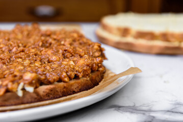 Putting caramel and nuts filling on a biscuit with spoon