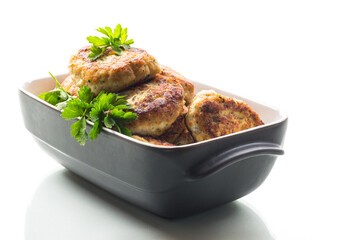 fried meat cutlets in a ceramic form on a wooden table