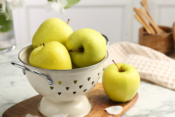Colander with fresh apples on white marble table