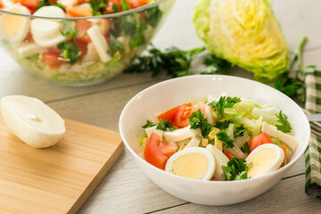 fresh vegetable salad, cabbage, tomatoes in a bowl on a wooden table