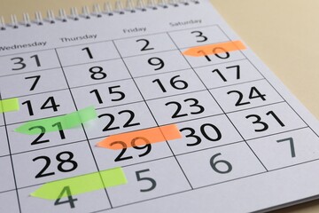Timetable. Calendar page with colorful sticky notes on beige background, closeup
