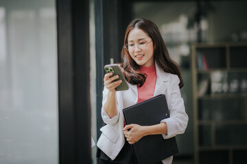 Beautiful attractive Asian businesswoman smiling and talking on mobile phone in office