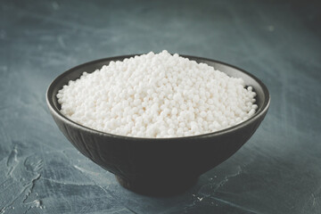 White Sago Pearls in Dark Bowl Also Know as Sabudana, Tapioca Pearl or Sago Seeds isolated on Gray Background