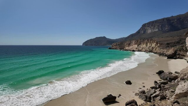 The concealed allure of Al Fizayah hidden beach in Salalah town of Oman. Top view panorama of its pristine white sands meeting crystal-clear waters. Breathtaking coastal scenery.