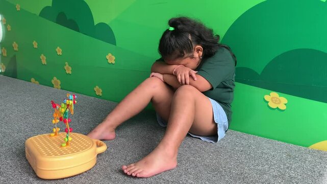 Sad depressed asian little girl siiting with her toys