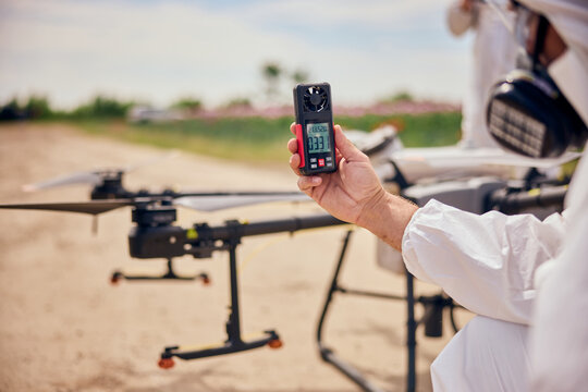 A male operator used an anemometer before flying an agrodrone over the poppy seeds field.