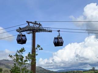 Two cable cars are suspended from a tall pole