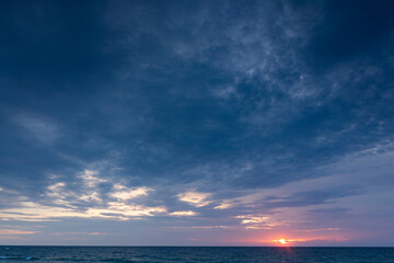Fototapeta premium low sun through the clouds, dark ocean